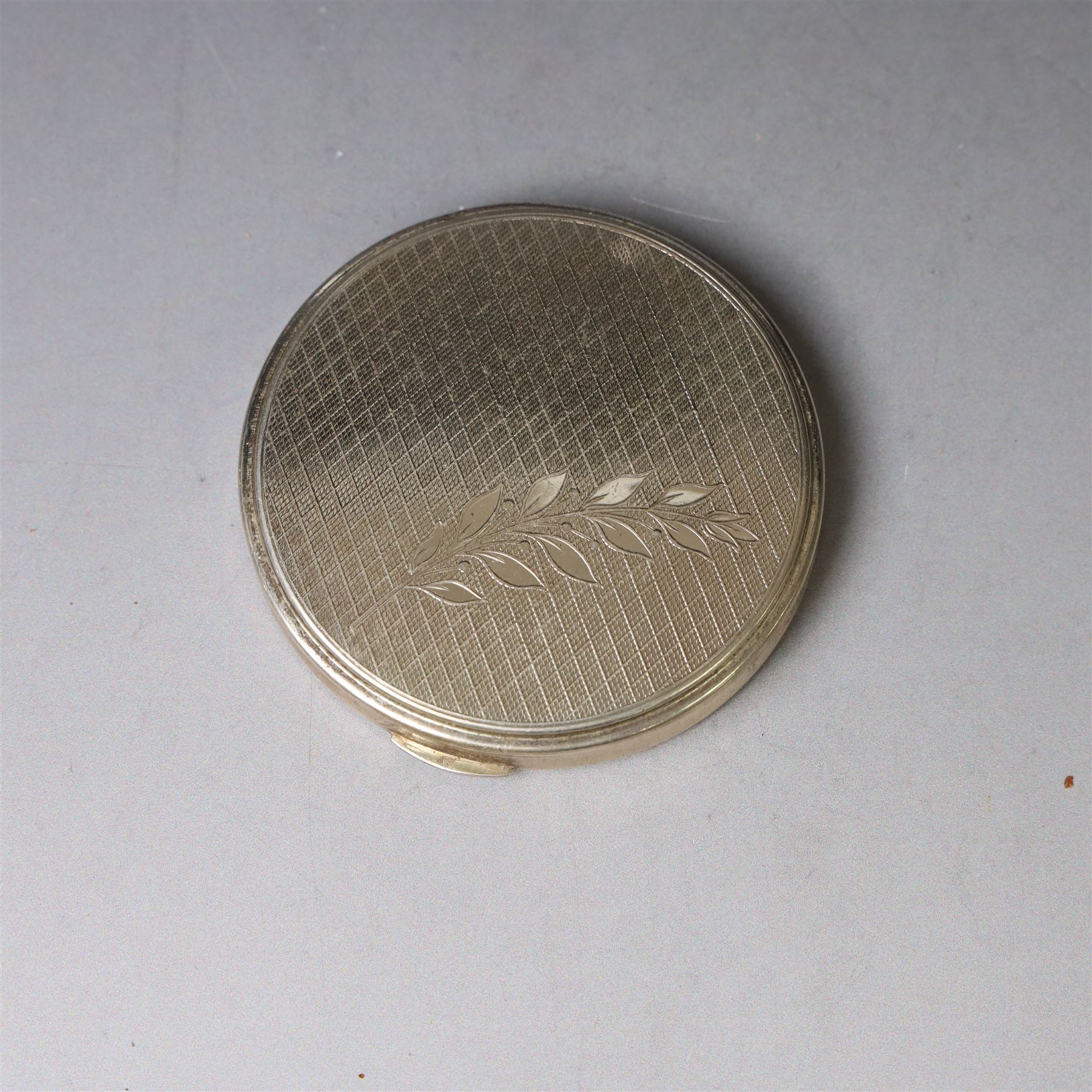 1960s silver compact mirror, of circular form with engine turned and engraved foliate decoration to lid, hallmarked Kigu Ltd, London 1963 and an early 20th century silver cigarette case with engraved monogram to cover, hallmarked A J Pepper & Co, Birmingham 1918