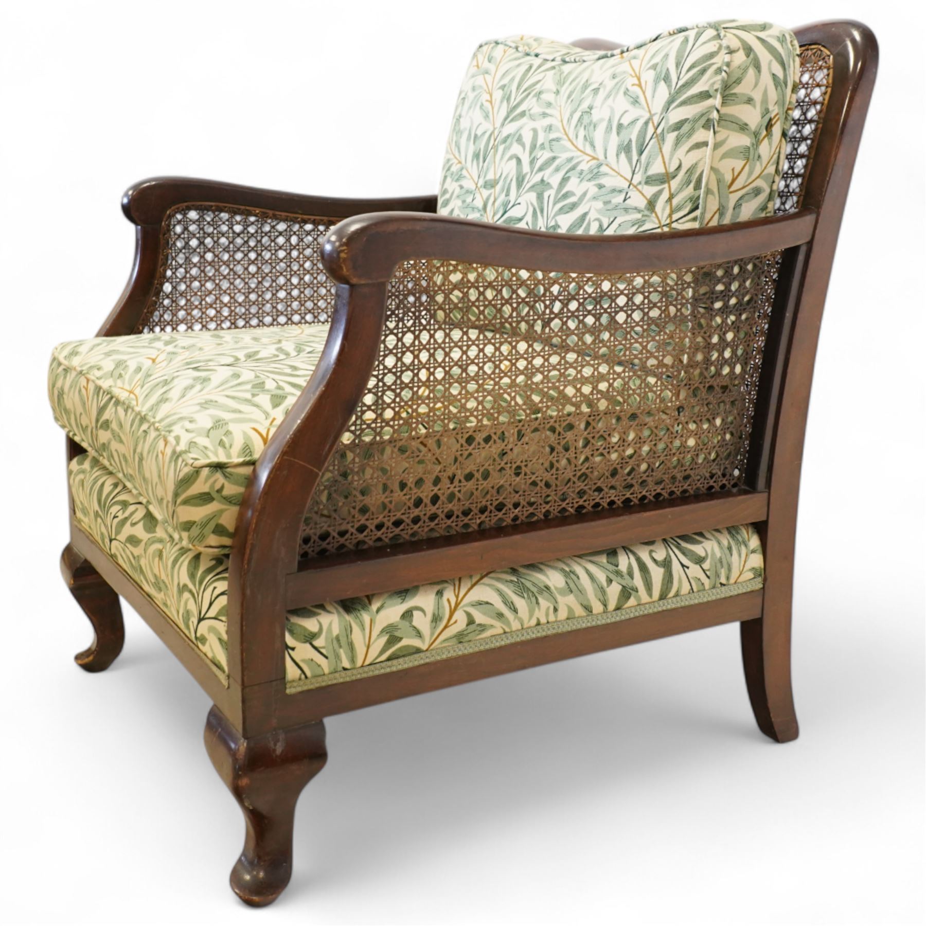 Edwardian stained beech Bergère armchair, with double cane sides and back, with the apron seat and cushion seat and back cushion, upholstered in a William Morris Willow Bough fabric, supported on cabriole legs with pad feet 