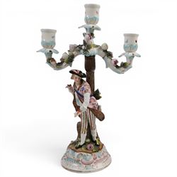 Pair of 19th Century German three-branch figural candlesticks, the figures each in floral dress against a tree, the branches decorated in relief with roses and the sconces painted with insects, H33cm 