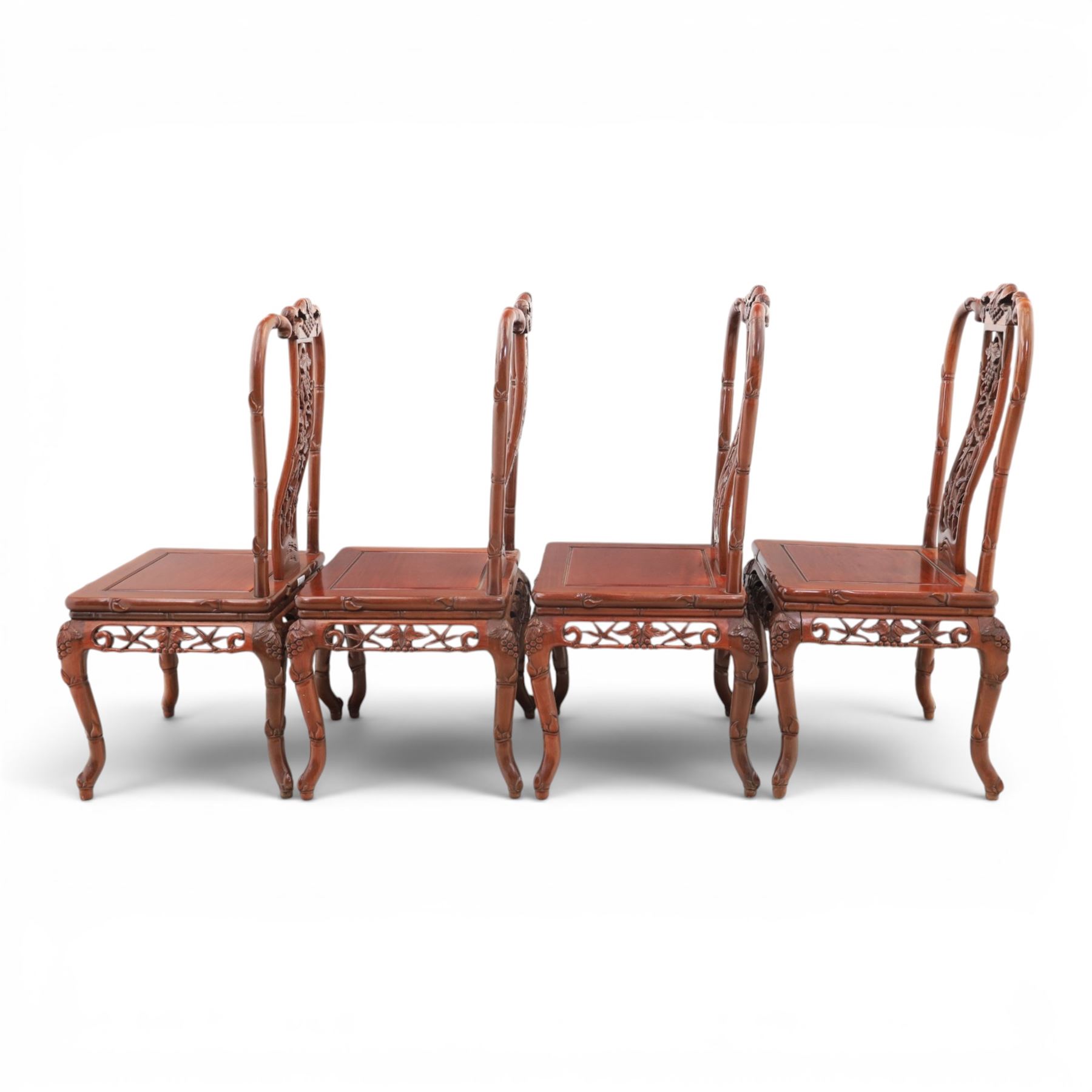 20th century Chinese ornately hardwood dining table and chairs, circular table with 'Lazy Susan' top with pierced carved frieze, raised on a quadriform base with carved foliate detail, the chairs en suite with carved pierced detailing  
