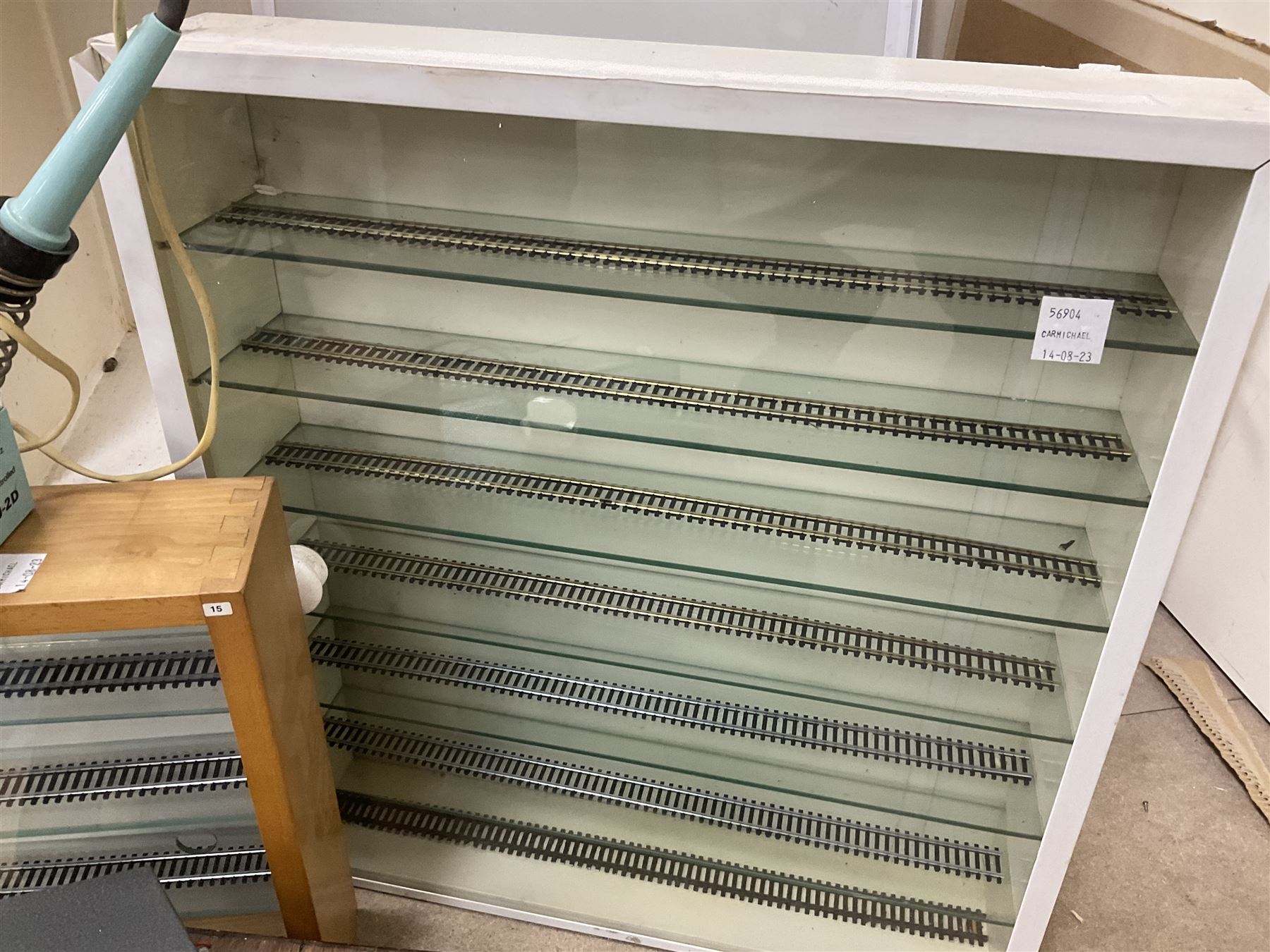 Six shelved cabinets for displaying ‘00’ gauge locomotives comprising plain plywood and white painted examples with track applied to various shelves, largest H63cm, W107cm, D27cm; Collection of tools for building model locomotives to include Weller PU-2D Soldering Pencil and Standard Tip Soldering Iron 20W/230V, Humbrol Modellers Airbrush, Power Supply Units and two wooden chests one of which housing a collection of tools including tweezers, scalping tools, wrenches etc 