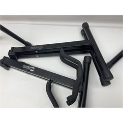 Four folding tubular guitar stands, two by RockJam; and folding tubular saxophone stand (5)