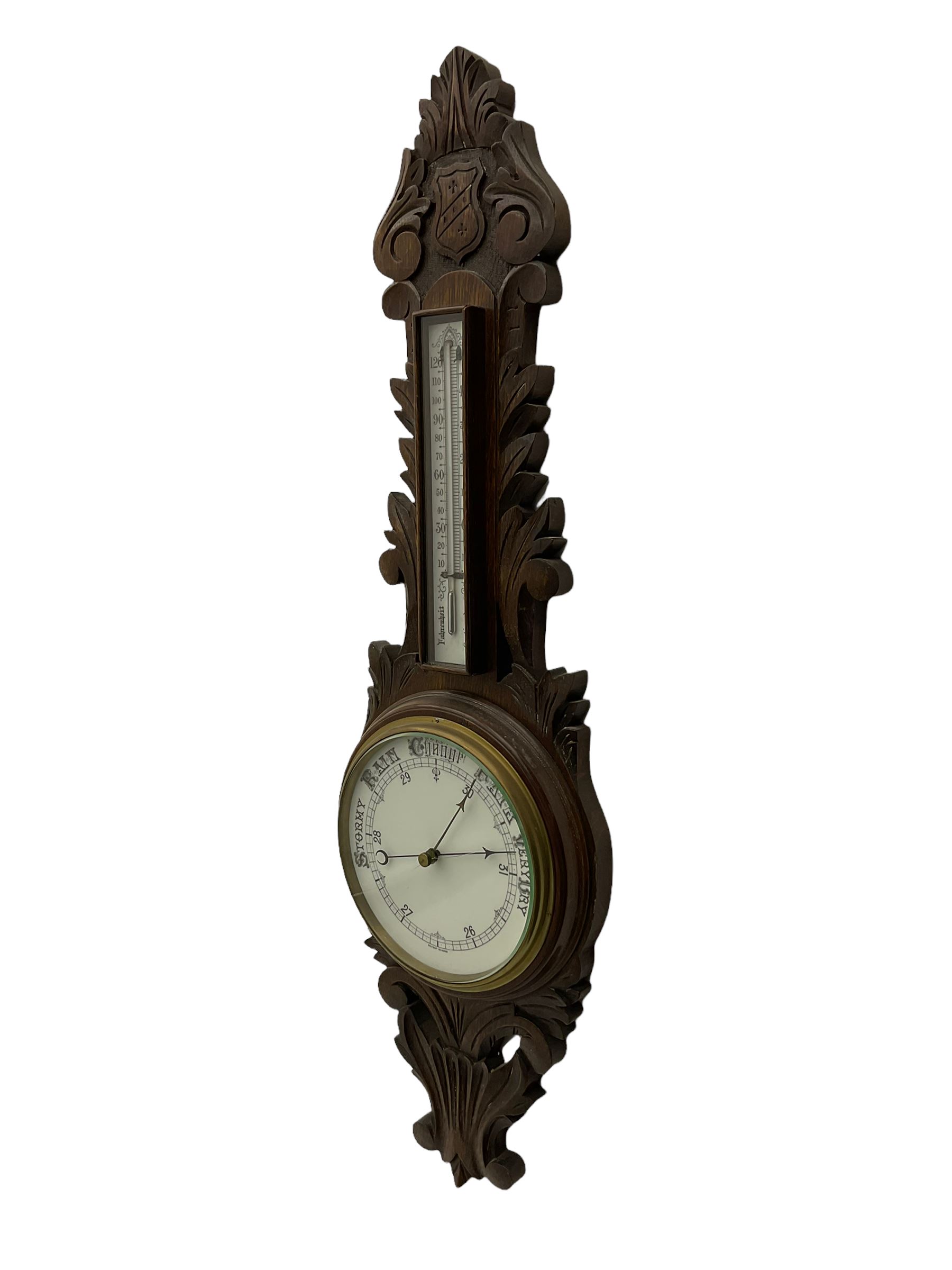 A 1920s oak cased patented aneroid barometer with openwork decorative carving, 8” enamel dial recording air pressure from 26 to 32 inches with weather predictions in gothic script, steel indicating hand and brass recording hand within a brass bezel and flat glass (glass cracked), with a boxed mercury thermometer recording the temperature in degrees centigrade and Fahrenheit.    

