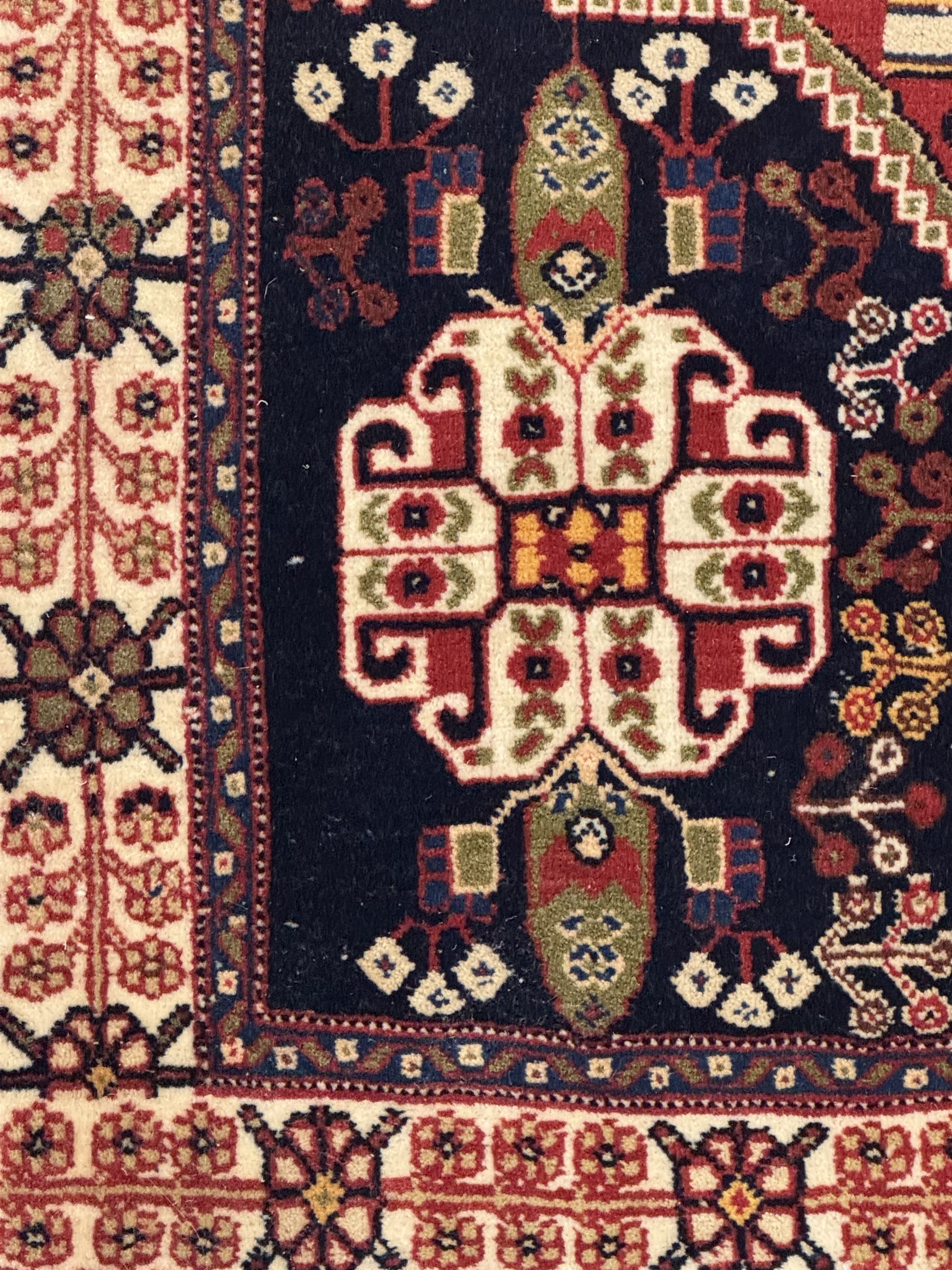 Fine Persian Qashqai crimson and navy ground runner, three large medallions filled with geometric and floral designs, the field with angular vines and stylised floral decoration, wide ivory border decorated with repeating floral and angular motifs