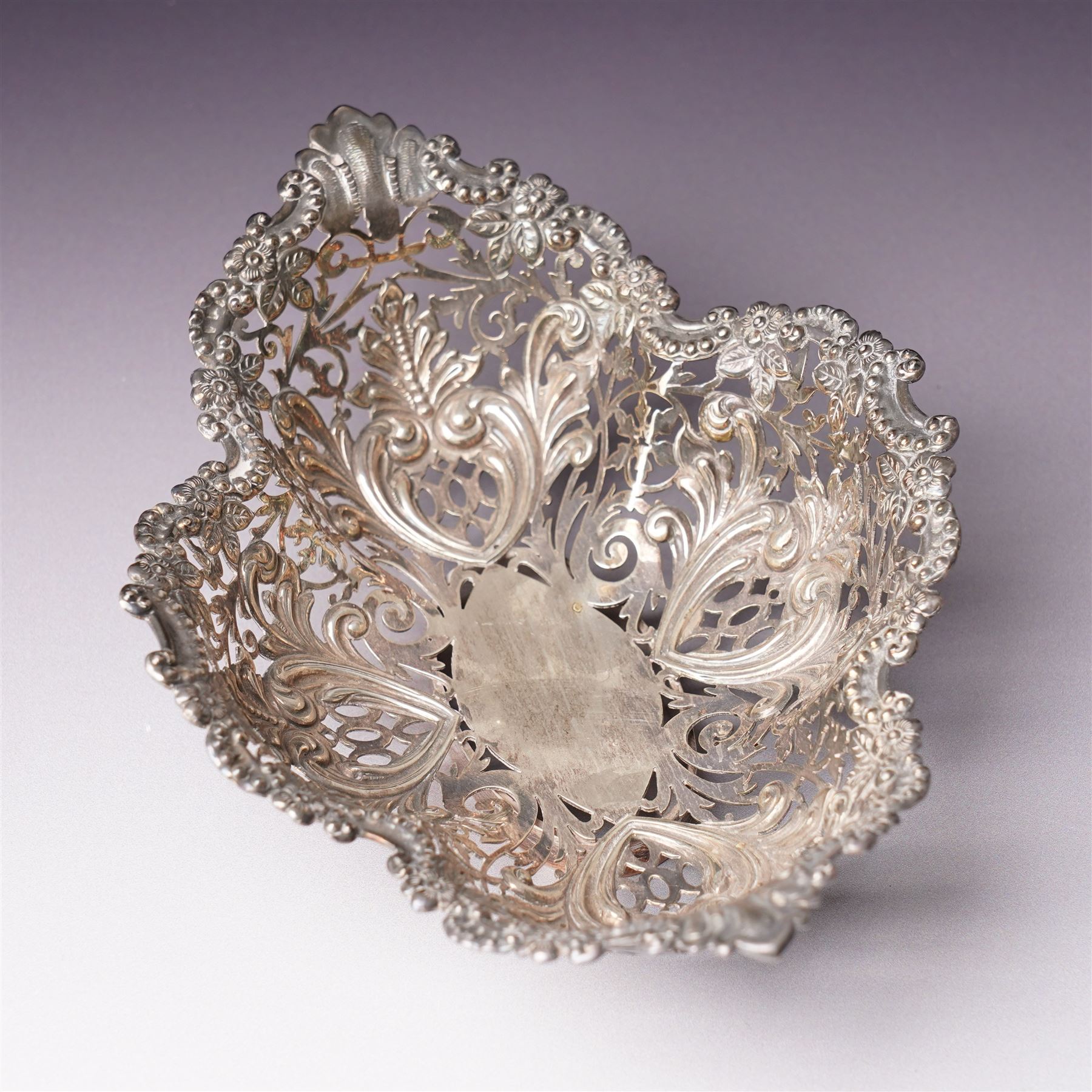 Edwardian silver oval dressing table box, the hinged cover embossed with angel heads W10cm London 1902 Maker William Comyns & Sons and an Edwardisn pierced silver oval sweetmeat basket L18cm Sheffield 1907 Maker James Dixon & Sons Ltd