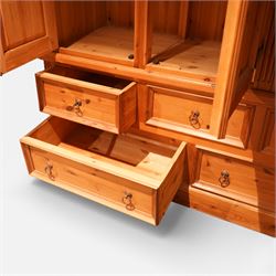 20th century pine wardrobe with drawer base, moulded cornice over three fielded panel cupboard doors enclosing hanging compartments, the base fitted with three short and two long drawers with brass ring handles, raised on a plinth base