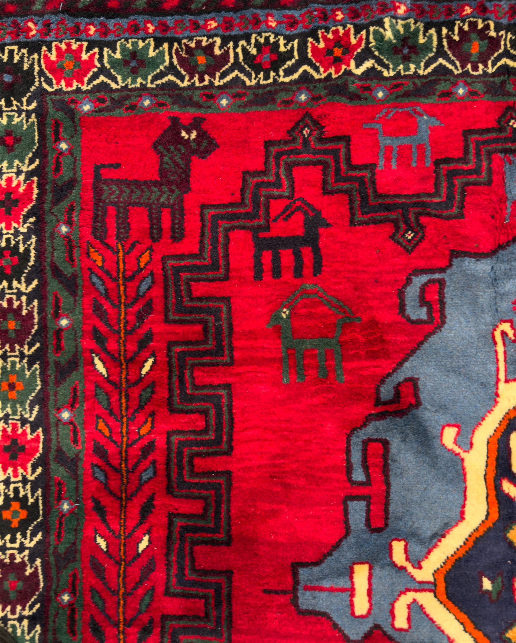 Northwestern Persian Cirjan hand-knotted carpet, madder red field with three linked stepped lozenge medallions in blue, ivory and green, flanked by angular motifs within a dark green border of serrated leaves and rosettes 