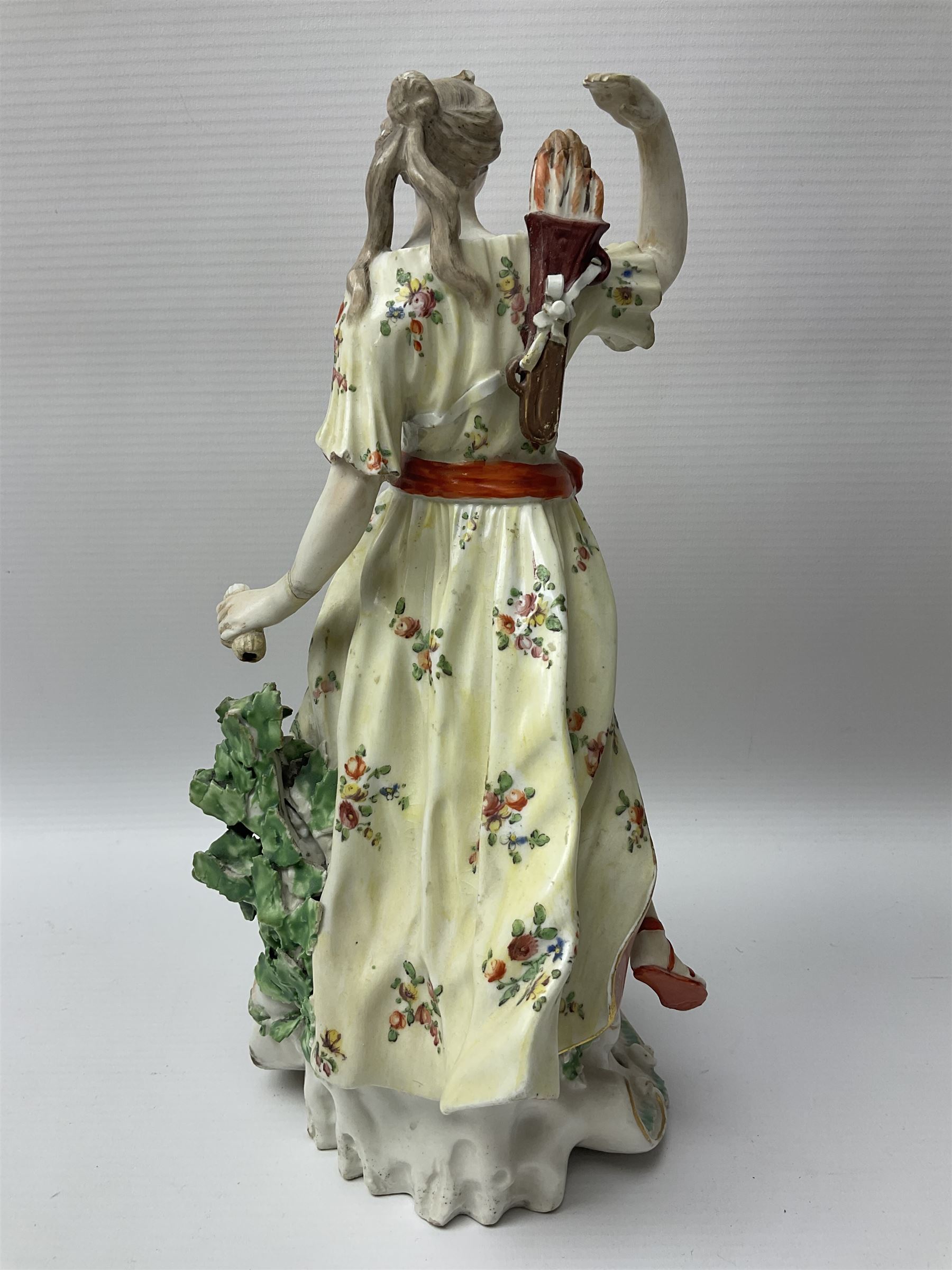18th century Derby figure of Diana the huntress, circa 1760, modelled reaching for an arrow from quiver across her back, with recumbent hound at her feet, upon a scrolled base with bocage detail, H27.5cm