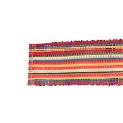 South West Persian Jajim kilim flatweave runner, woven in warp-faced flatweave and composed of narrow bands, striped field in various shades of rose, coral, ivory, indigo, turquoise, and olive, embellished along the sides with applied knotted wool rosettes and tassels, some missing (due to large size, the runner is illustrated in two sections)