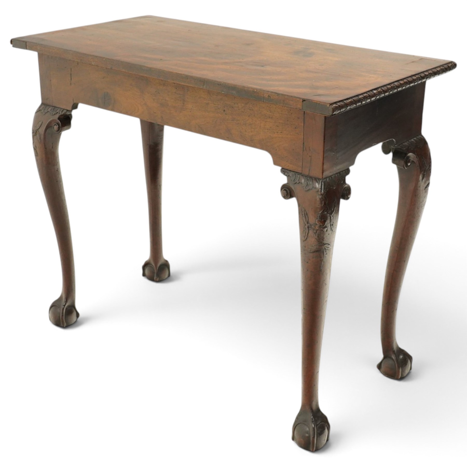 George I carved mahogany side table, adapted from a card table, the rectangular top with foliate-carved edge above a plain frieze, raised on cabriole legs with acanthus-carved knees, volute brackets and floral-carved motifs, terminating to ball-and-claw feet
