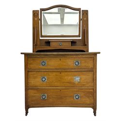 Early 20th century Arts and Crafts oak dressing chest, the arched mirror flanked by floral marquetry inlaid uprights above a shelf and drawer, over three long drawers with square hammered metal plates and circular pulls, on slender supports with castors