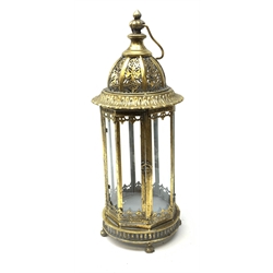 A bronzed effect metal lantern, of hexagonal form with glass panels, pierced domed top and carry handle, raised upon four paw feet, excluding carry handle H54cm.