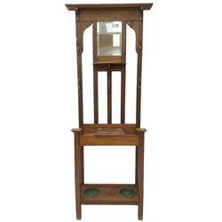 Edwardian oak hall stand, raised back with rectangular bevelled mirror plate surrounded by shelf and coat hooks, fitted with a glove box with hinged lid, over an undertier with two inset umbrella drip trays
