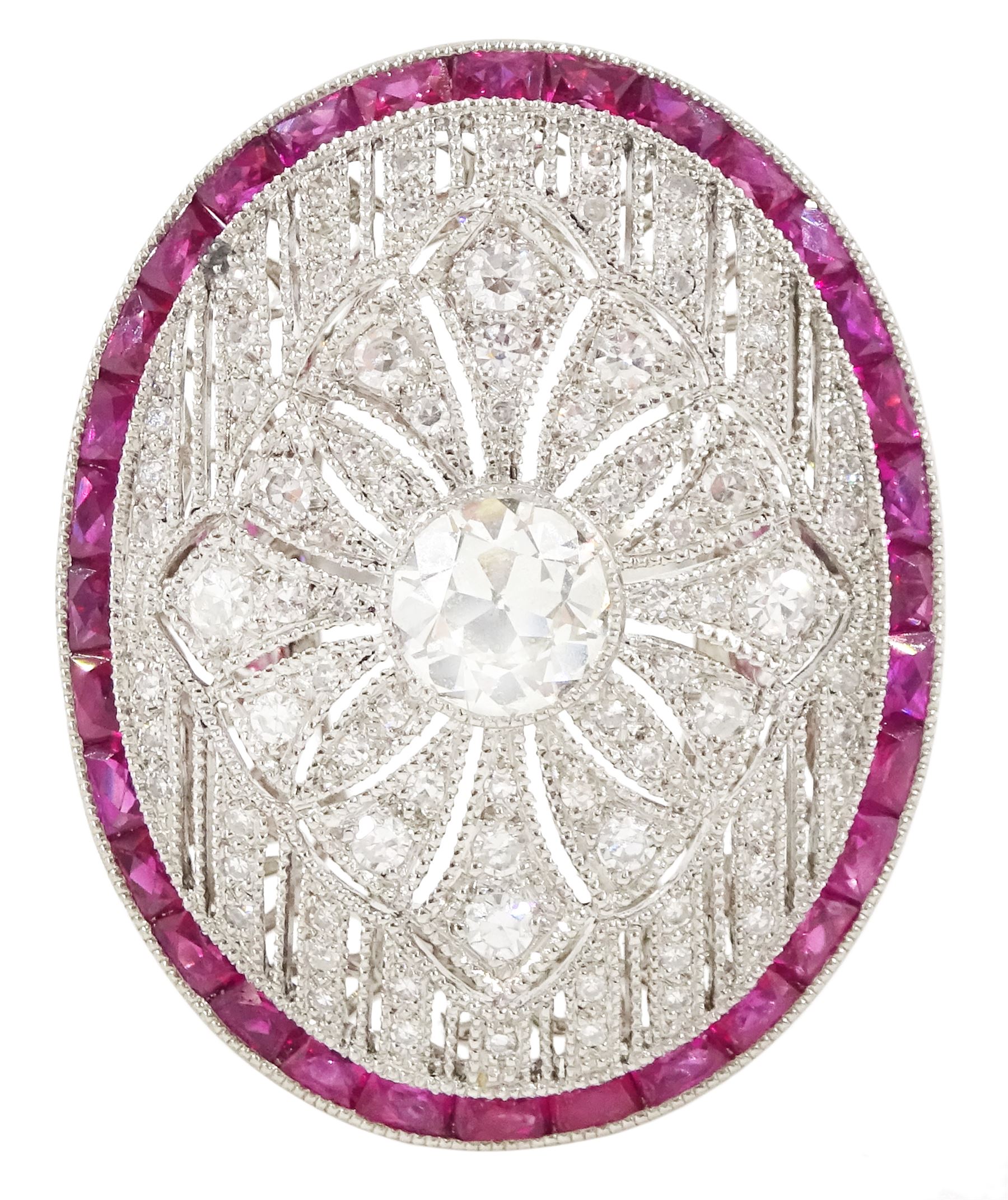 Platinum diamond and ruby oval cluster ring, principal transitional cut diamond of approx 0.55 carat, with milgrain set openwork diamond surround and calibre cut ruby border, with ruby and diamond shoulders