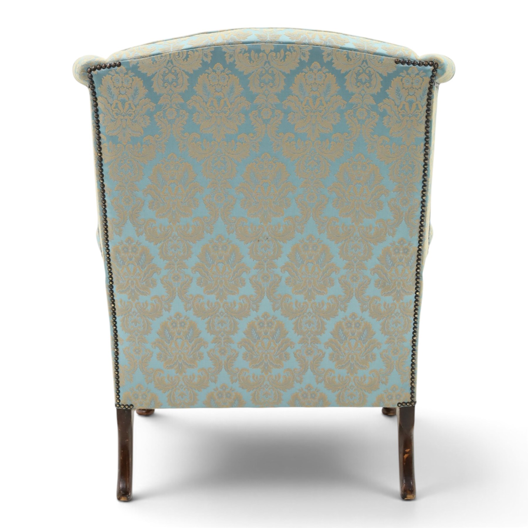 Georgian design carved mahogany framed wingback armchair, high wingback over sprung seat and loose cushion with rolled arms, upholstered in cyan ground gilt foliate damask fabric, on shell-carved cabriole supports with pad feet