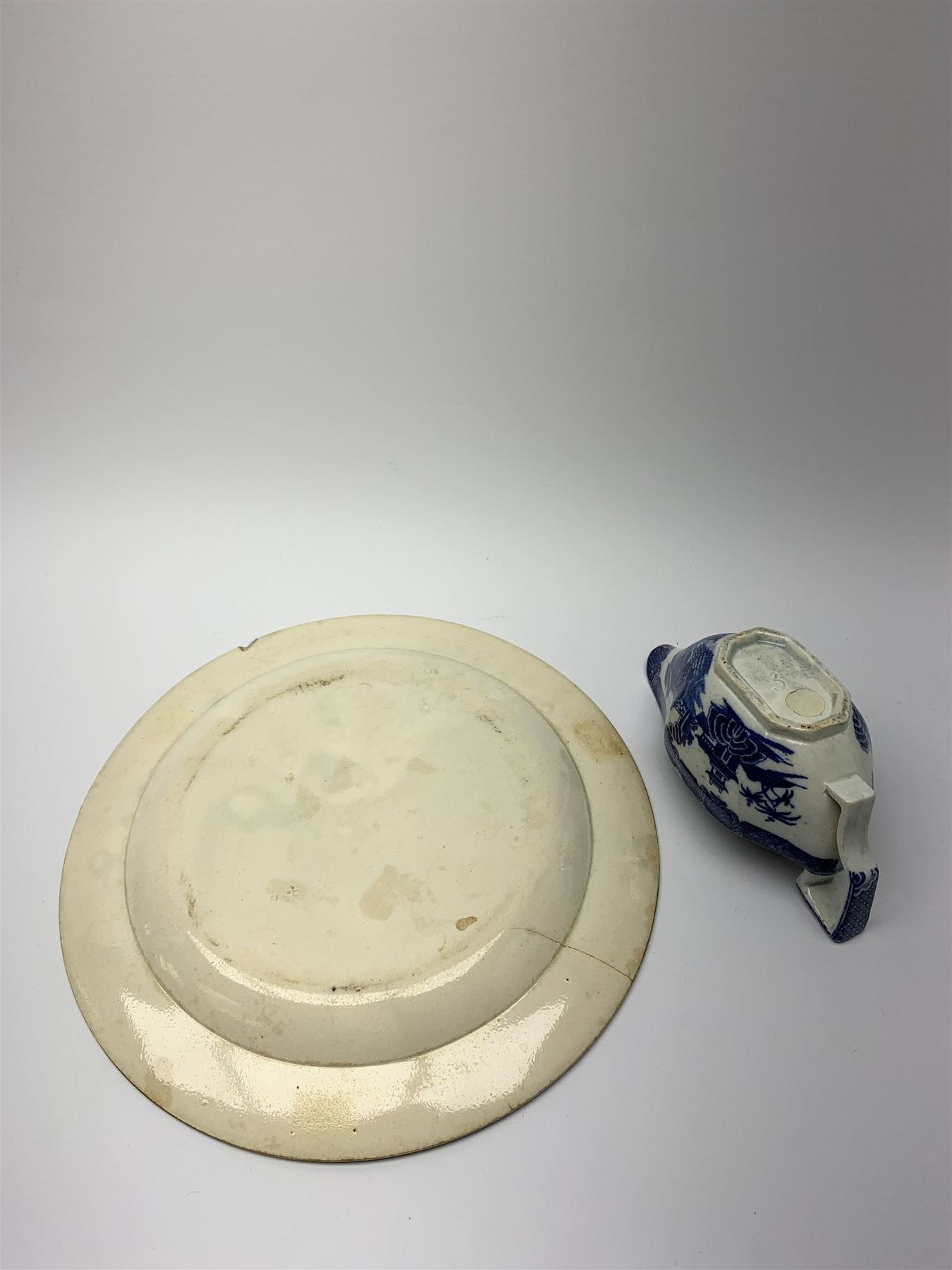 Early 19th century David Dunderdale & Co Castleford pottery plate, decorated in brown in the Buffalo and Ruins pattern, with indistinct impressed marks beneath, D24cm, together with a late 18th/early 19th century blue and white pearlware sauce boat, decorated in a variant of the Willow pattern, L15cm