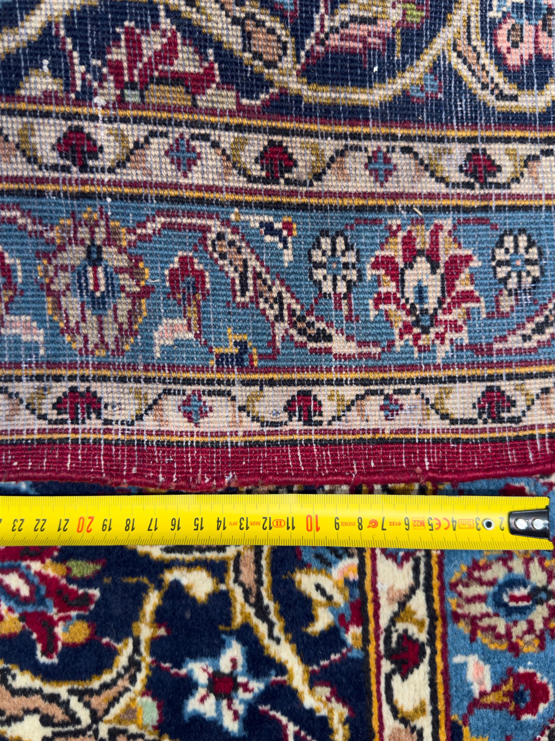 Northeastern Persian Meshed hand-knotted carpet, madder red field with an all-over design of scrolling vines, palmettes, and rosettes, within a dark blue border of palmettes and arabesques 