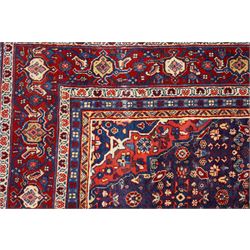 West Persian Mahal hand-knotted carpet, indigo field with central stylized angular medallion issuing an all-over Herati-inspired lattice of floral sprays, rosettes and geometric vinery in tone soft madder red, ivory and soft blue, principal border decorated with stylized palmettes, and angular vine motifs, flanked by multiple guard borders, with cotton fringe ends 