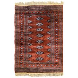 Persian Bokhara burnt amber ground rug, the field decorated with indigo lozenge shaped Gul motifs, within a guarded border of further repeating Gul designs