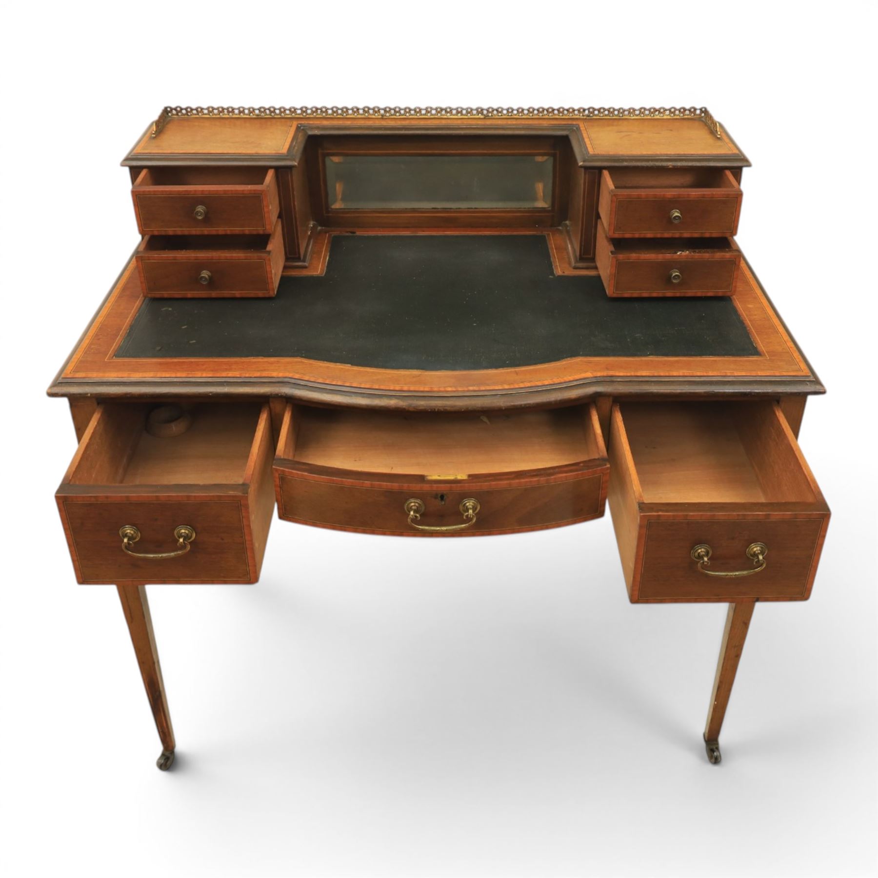 Maple & Co - Edwardian mahogany inlaid writing desk, the superstructure with pierced brass gallery, above an inset mirror and two short drawers, inset leather writing surface, bow fronted with crossbanded drawers and brass swan neck handles, square tapering supports terminating in castors 