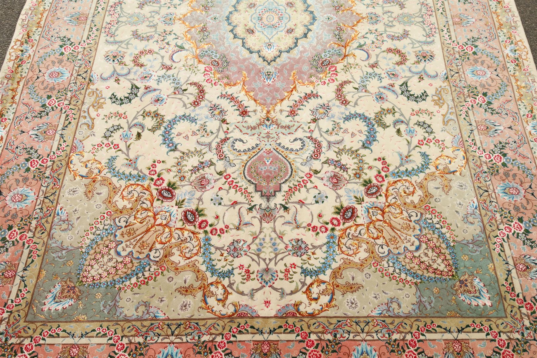 Fine Persian silk inlaid ivory and rose ground Tabriz rug, the busy field decorated with a central foliate pole medallion surrounded by scrolling foliage with trailing flowerheads and bouquets, the multiple guard lines filled with repeating scrolling palmettes and interlocking floral motifs