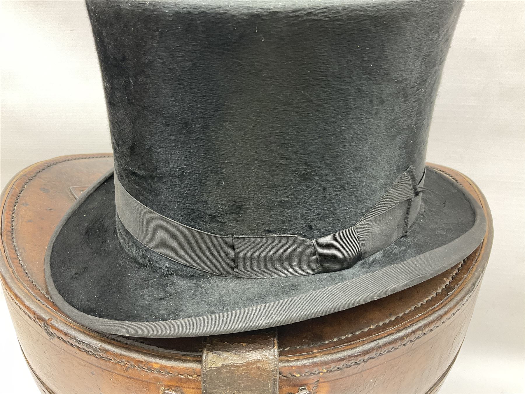 Early 20th century black silk top hat by Woodrow of Manchester and London, with manufacturer's stamp to the silk lined interior, housed in fitted tan leather hat box with removable internal compartments with straps, brass escutcheon and engraved plaque, hat internal measurements approx 20cm x 15cm