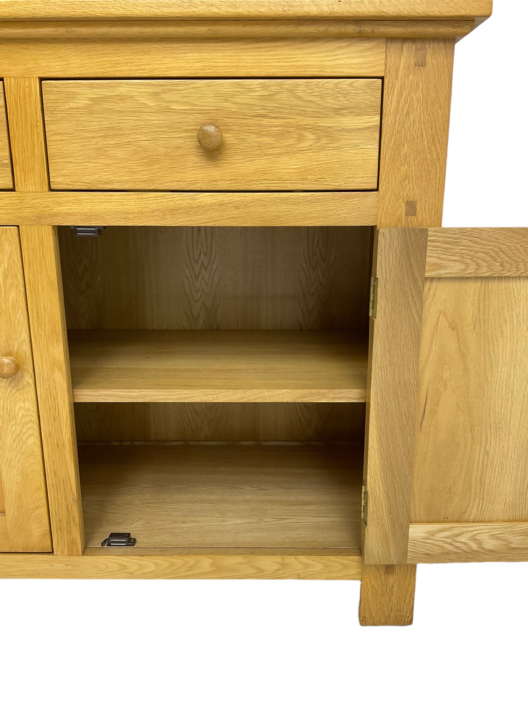Contemporary light oak bookcase display cabinet, fitted with  two glazed doors enclosing two shelves, above two drawers and cupboards