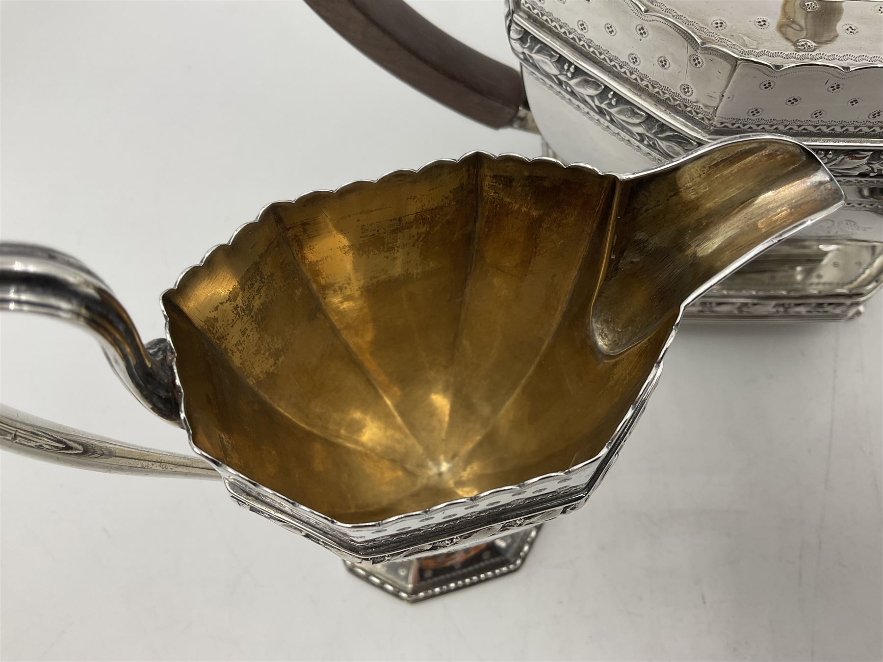 Victorian silver four piece tea service, comprising teapot, teapot stand, twin handled open sucrier and milk jug, each of octagonal form with foliate bud border and engraved decoration including crest to canted panels, and vacant panels, the teapot with ivory finial to the hinged cover and later wooden handle, hallmarked Edward Barnard & Sons Ltd, London1896, teapot including finial H15cm, milk jug including handle H16cm, teapot stand W11.5cm

This item has been registered for sale under Section 10 of the APHA Ivory Act