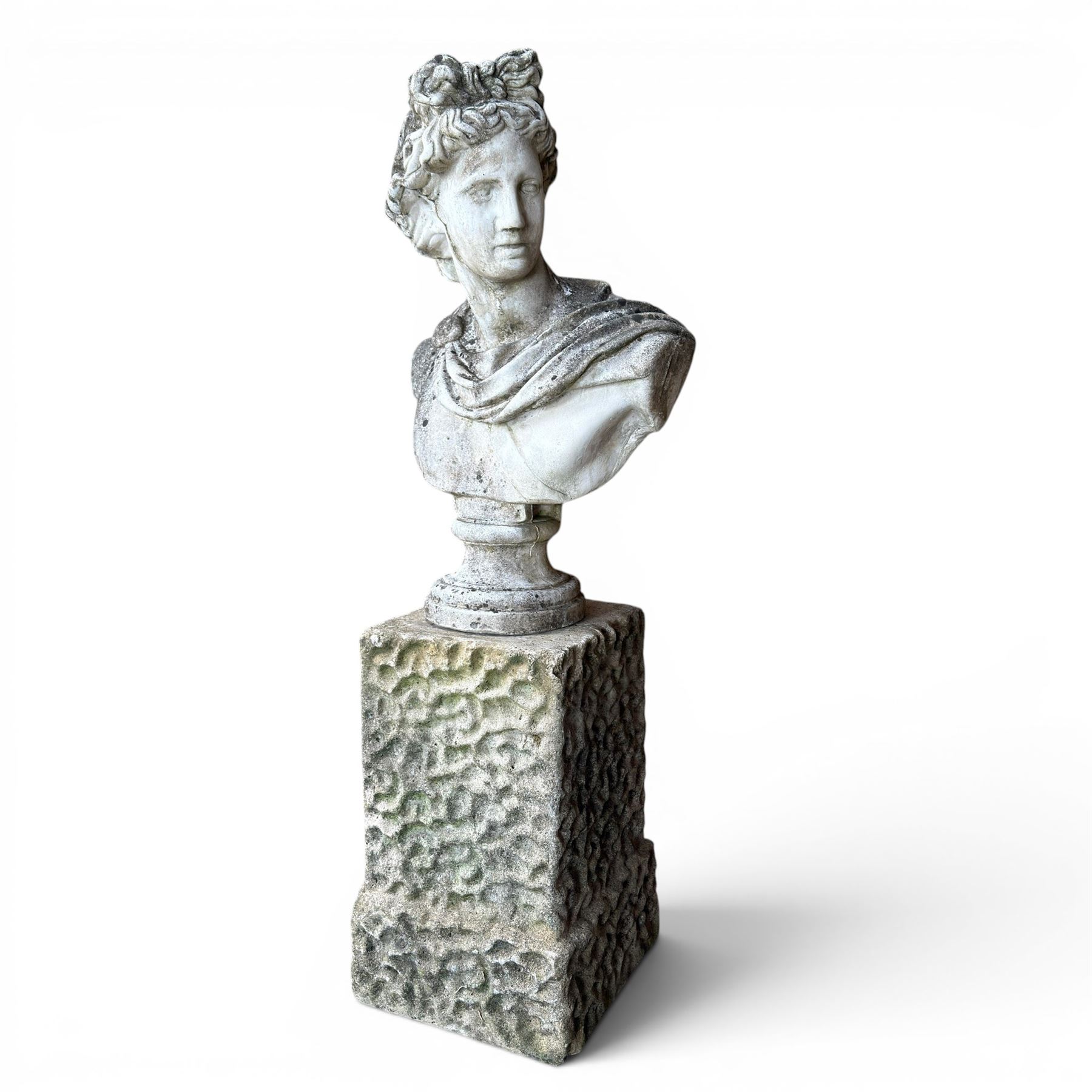 Roman Neoclassical style cast stone bust, weathered finish, raised on textured stone plinth of tapering form