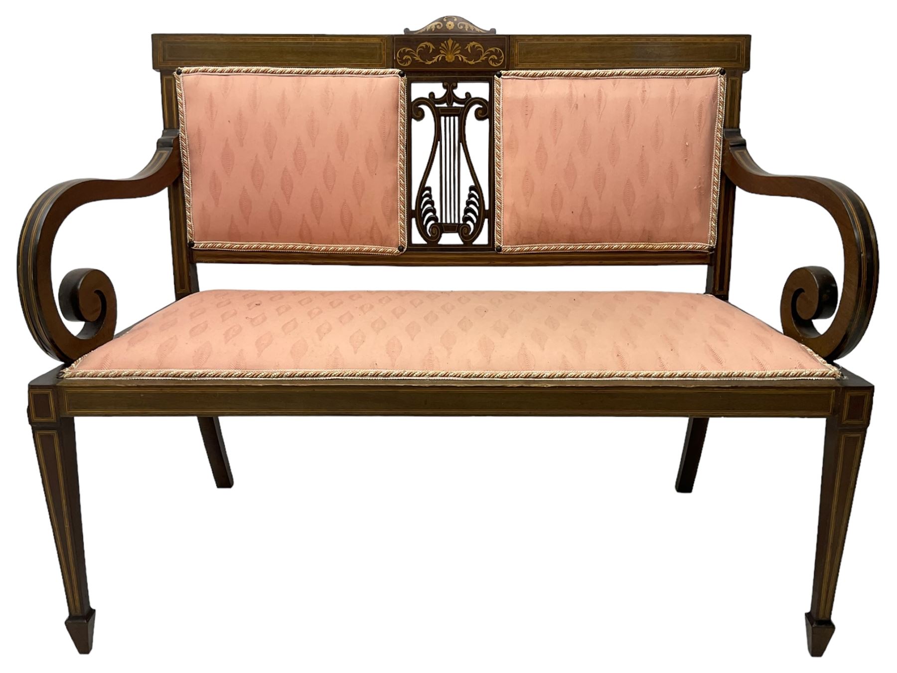 Edwardian inlaid mahogany two-seat settee or hall bench, the cresting rail inlaid with satinwood banding and boxwood stringing, central panel inlaid with scrolled leafy branches over pierced and carved lyre back, upholstered in peach fabric with repeating pattern, scrolled down sweeping arms, on square tapering supports with spade feet 