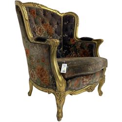 Pair of Louis XVI design gilt framed wingback armchairs, cresting rail carved and moulded with foliate decoration and C-scrolls, upholstered in buttoned floral patterned mauve velvet with loose seat cushion, scallop carved apron over cabriole supports