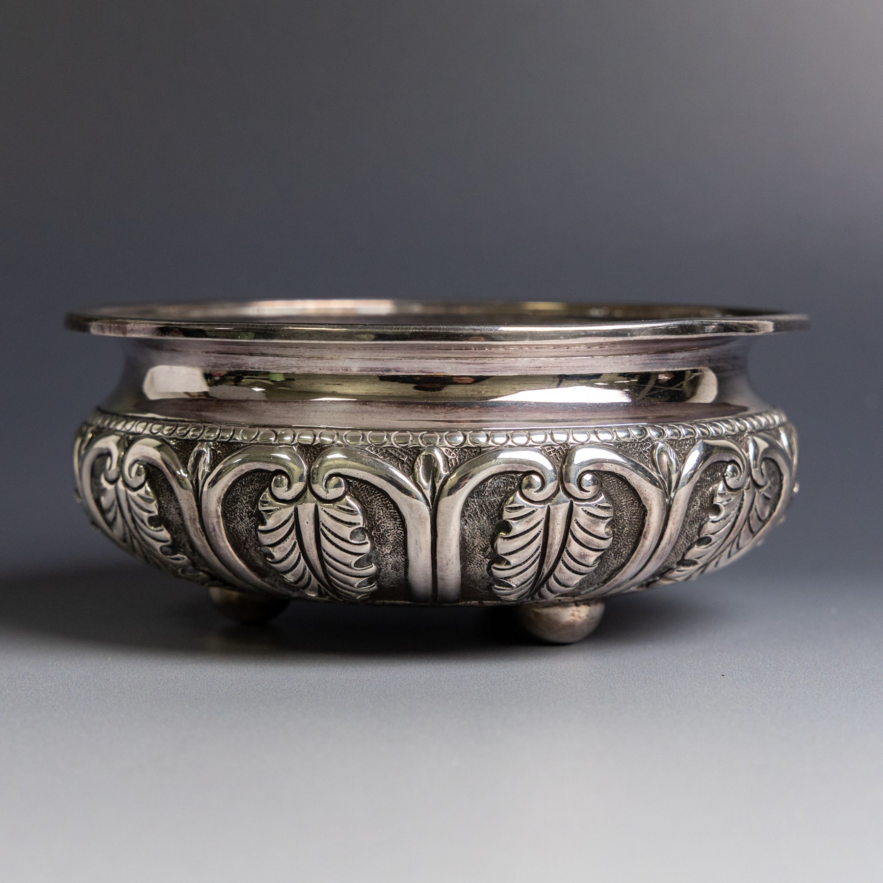 Indian silver bowl, of circular form with embossed acanthus leaf decoration, upon three bun feet, D5.5cm, H13cm