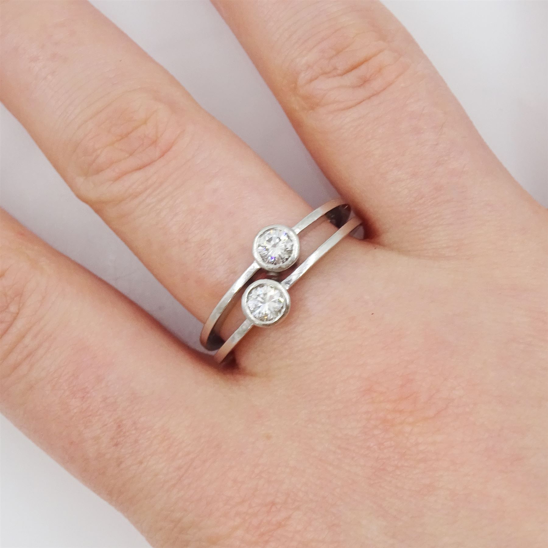 Platinum bezel set, two stone round brilliant cut diamond, crossover ring, London 1985, total diamond weight approx 0.50 carat