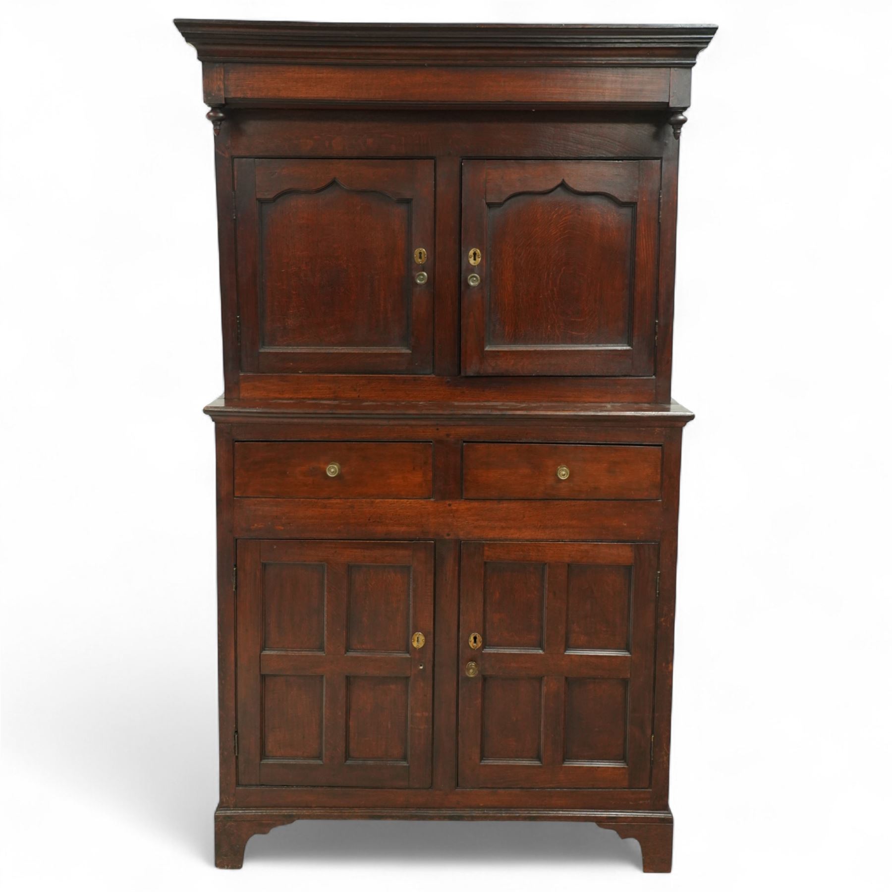 Early 19th century Welsh oak kitchen cupboard, the projecting cornice with twin cupboard doors, the rectangular base over two frieze drawers and panelled cupboard doors, raised on bracket feet, with fielded and arched panel variants to front and sides