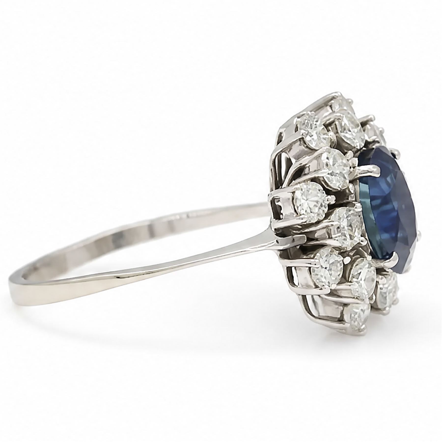 18ct white gold sapphire and diamond cluster ring, single oval cut sapphire of approx 2.10 carat, surrounded by sixteen round brilliant cut diamonds, total diamond weight approx 0.95 carat