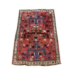 Persian red ground rug, decorated with stylised animal and floral motifs