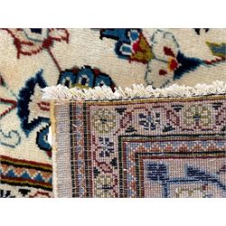 Persian Kashan ivory ground carpet, the field decorated with scrolling branches with foliate and palmette motifs, repeating border with stylised plant motifs, within floral and geometric pattern guard stripes 