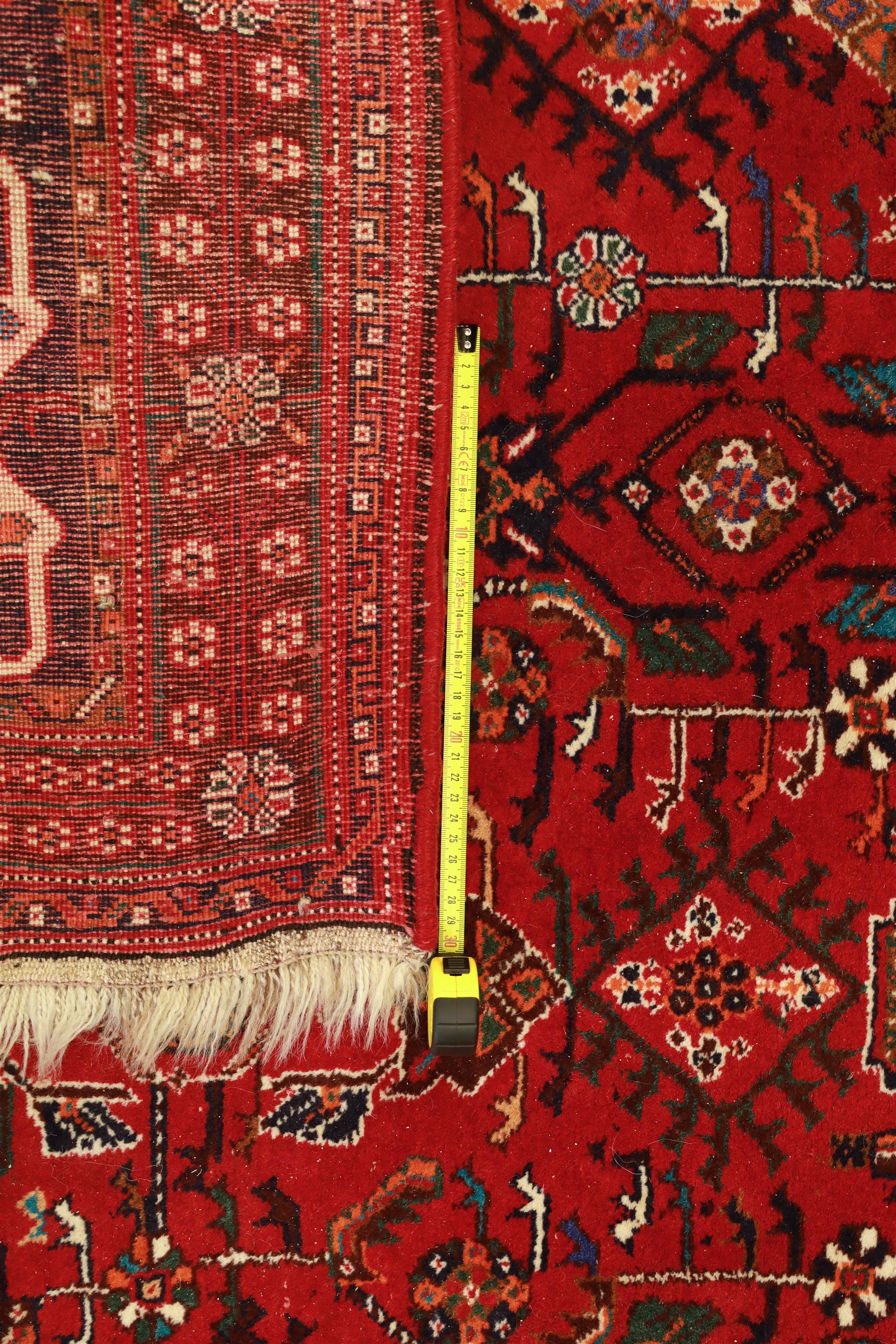 Persian tribal hand-knotted rug, crimson ground, madder field with central stepped lozenge medallion with scattered floral and geometric spandrels with rosette border 