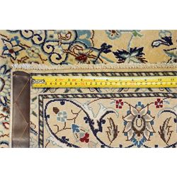 Central Persian Nain hand-knotted silk and wool rug, ivory field with a cusped medallion  issuing radiating pendants, with an all-over design of scrolling arabesques, palmettes and floral sprays, framed main border of meandering vinery and stylized palmettes, flanked by narrow guard stripes, cotton fringe ends  