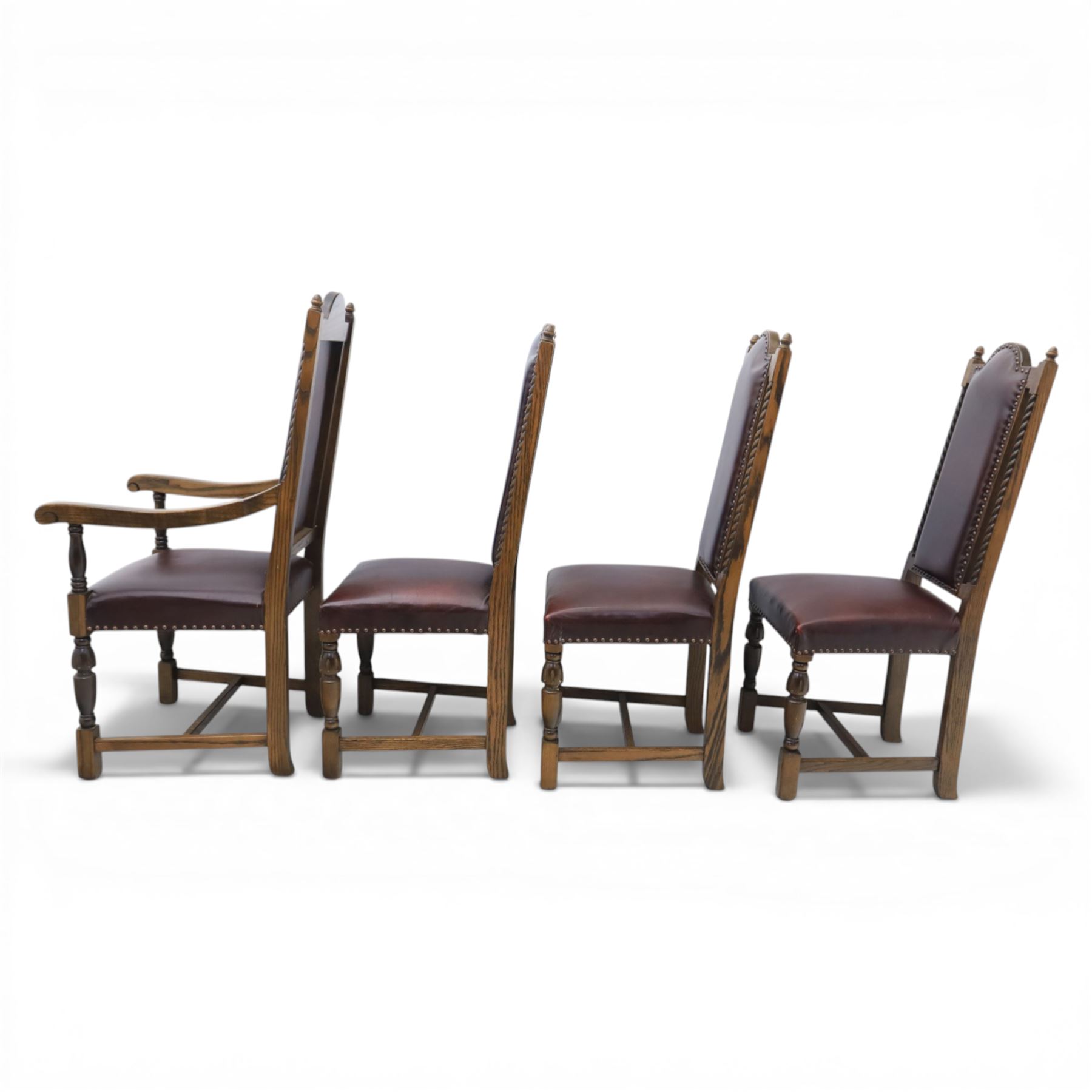 Carolean revival oak dining table and eight chairs (7+1), refectory table with rectangular boarded top and cleated ends, raised on shaped trestle end supports with central stretcher, accompanied by eight high-back chairs including a carver, leather upholstered panels and seats with studwork, on turned legs with stretchers.