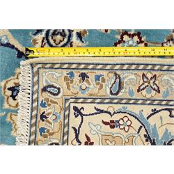 Central Persian Nain hand-knotted carpet, soft sky blue ground with central cusped medallion of radiating palmette form, issuing scrolling vine work, arabesques, and delicate floral sprays, spandrels of conforming design, main border of ivory ground decorated with scrolling vine work palmettes and stylized floral motifs, flanked by narrow guard stripes, with cotton fringe ends 