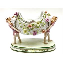 Continental ceramic centrepiece, in the style of Dresden, decorated with two fairies holding up an oval bowl with floral detail, with spurious blue crossed swords beneath, H26cm.    