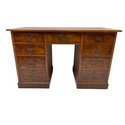 Late 19th to early 20th century walnut pedestal desk, rectangular top inset with red tooled leather writing surface, over a central frieze drawer flanked by two pedestals, each fitted with four graduated drawers with brass escutcheons and drop handles, the whole raised on a plinth base
