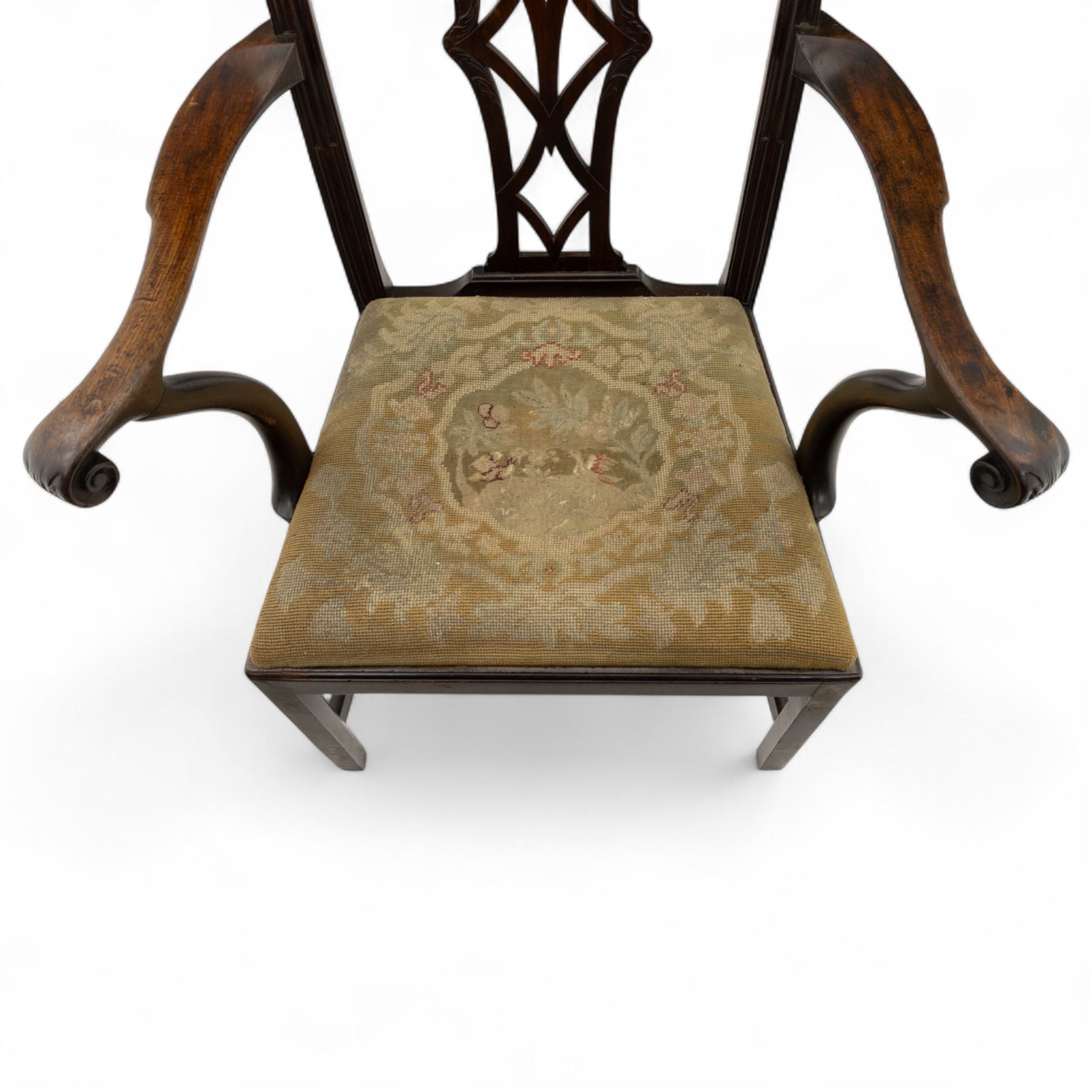 19th-century Chippendale Revival design mahogany oversized high-back armchair, serpentine crest carved top rail above pierced back splat with interlaced ribbon carving and geometric fretwork design, and outward scrolling arms above drop-in needlework seat on square chamfered legs 