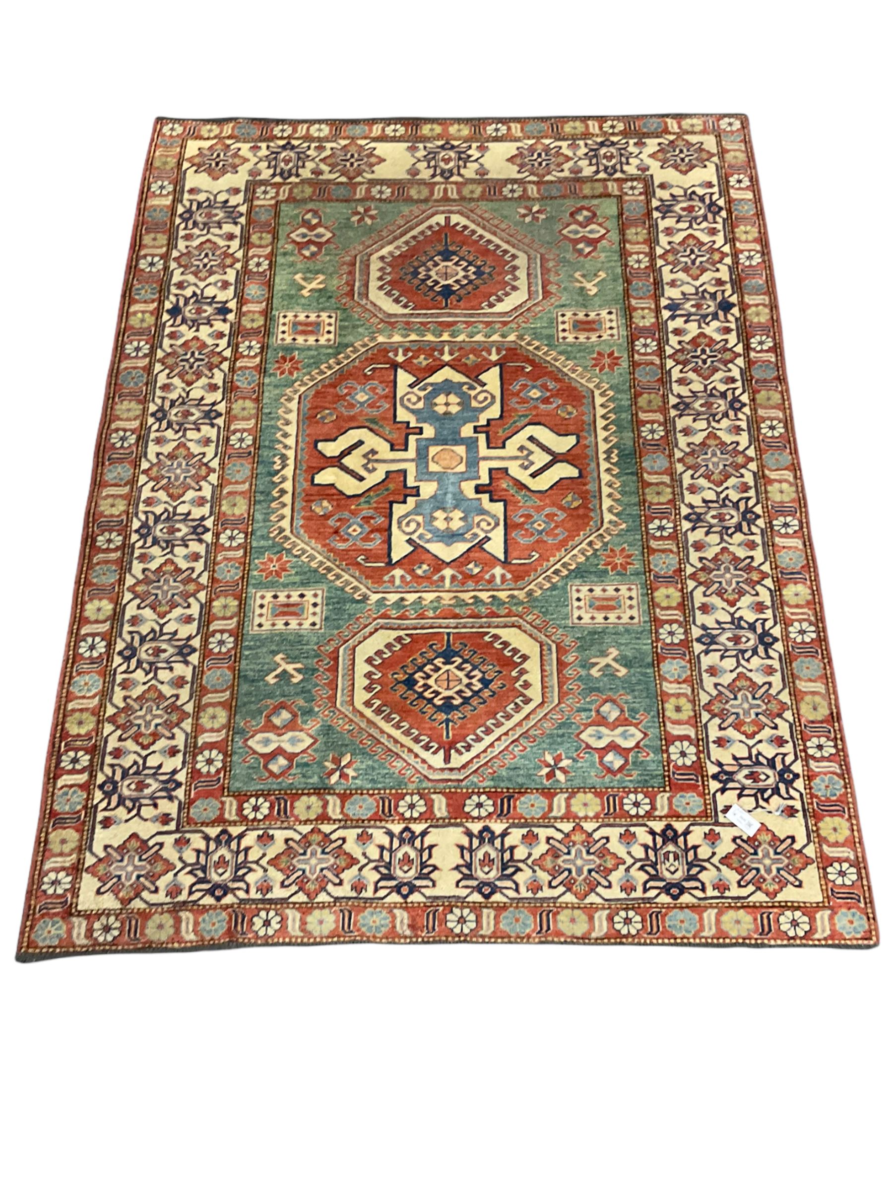 Kazakh rug, pale green ground field with three part medallion, three band border decorated with stylised plant motifs