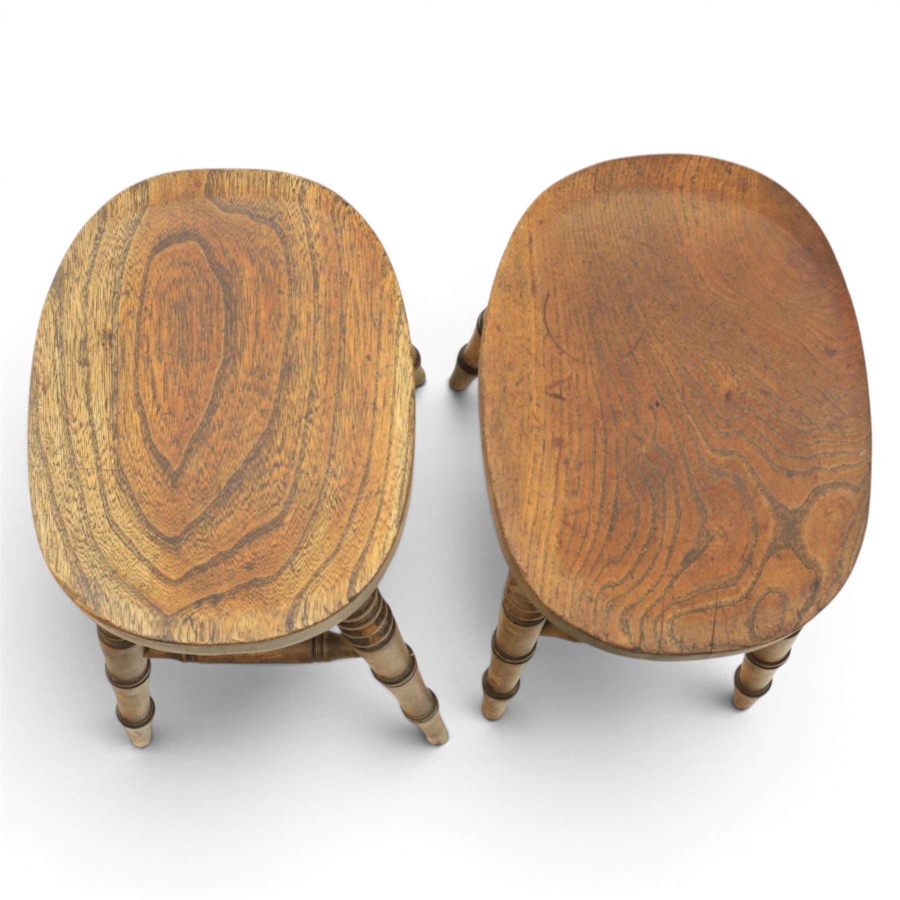 Pair of country elm stools, with oval dished seat raised on turned wooden supports, united by a H-stretcher