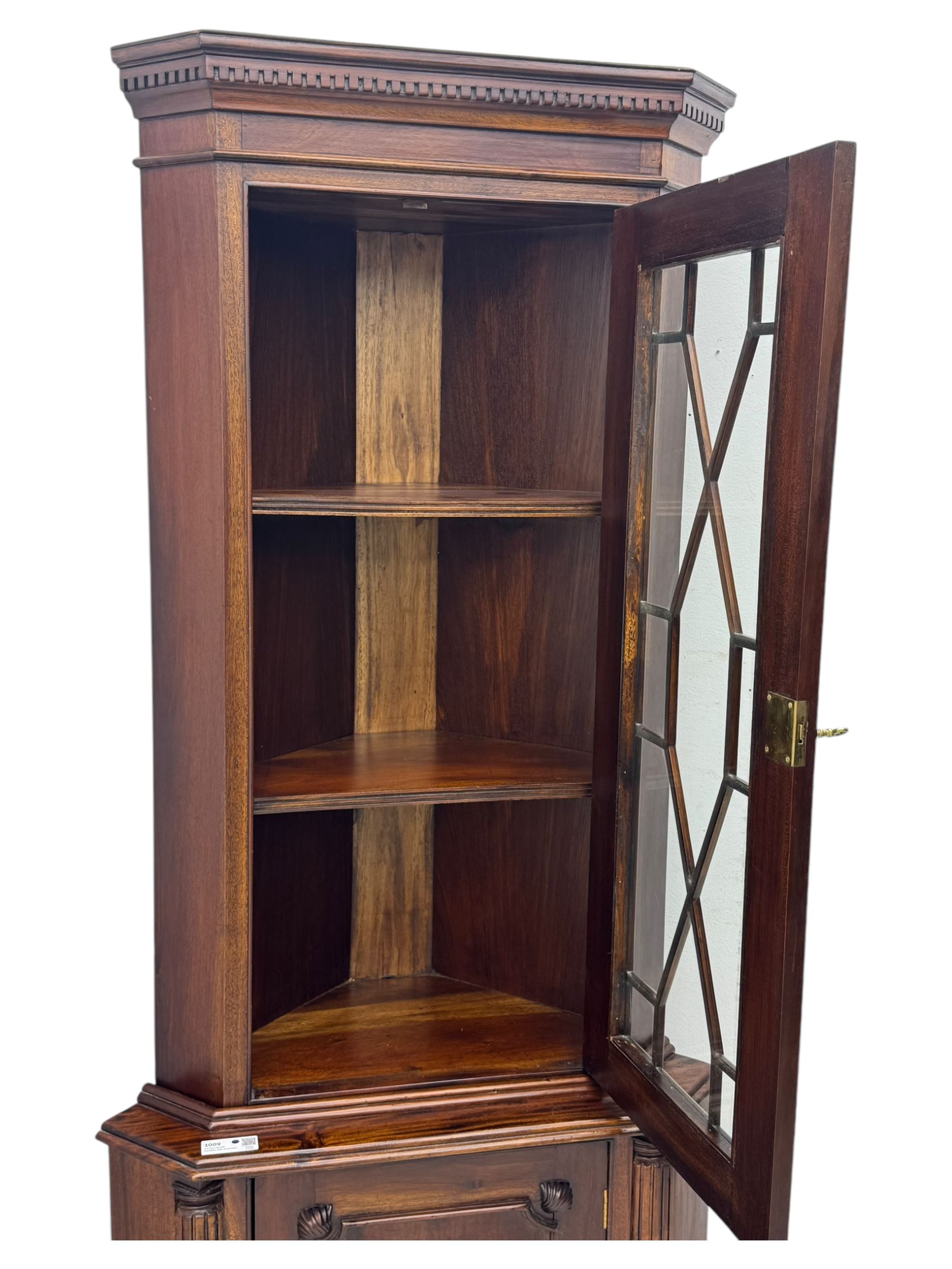 Late 20th century mahogany corner cabinet, dentil moulded cornice above a glazed door with astragal glazing enclosing two shelves, lower cupboard with fielded panel door and turned shell motif, on plinth base