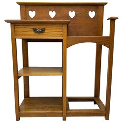 Arts and Crafts period golden oak hallstand, raised back with pierced heart decoration, fitted with glove drawer over two shelves, beside umbrella stand