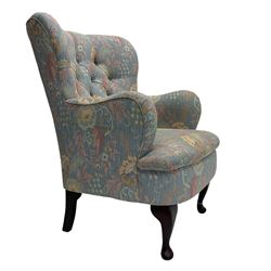 Mid-20th century wingback armchair, upholstered in soft blue floral patterned fabric with button-tufted backrest and curved arms and raised on cabriole supports