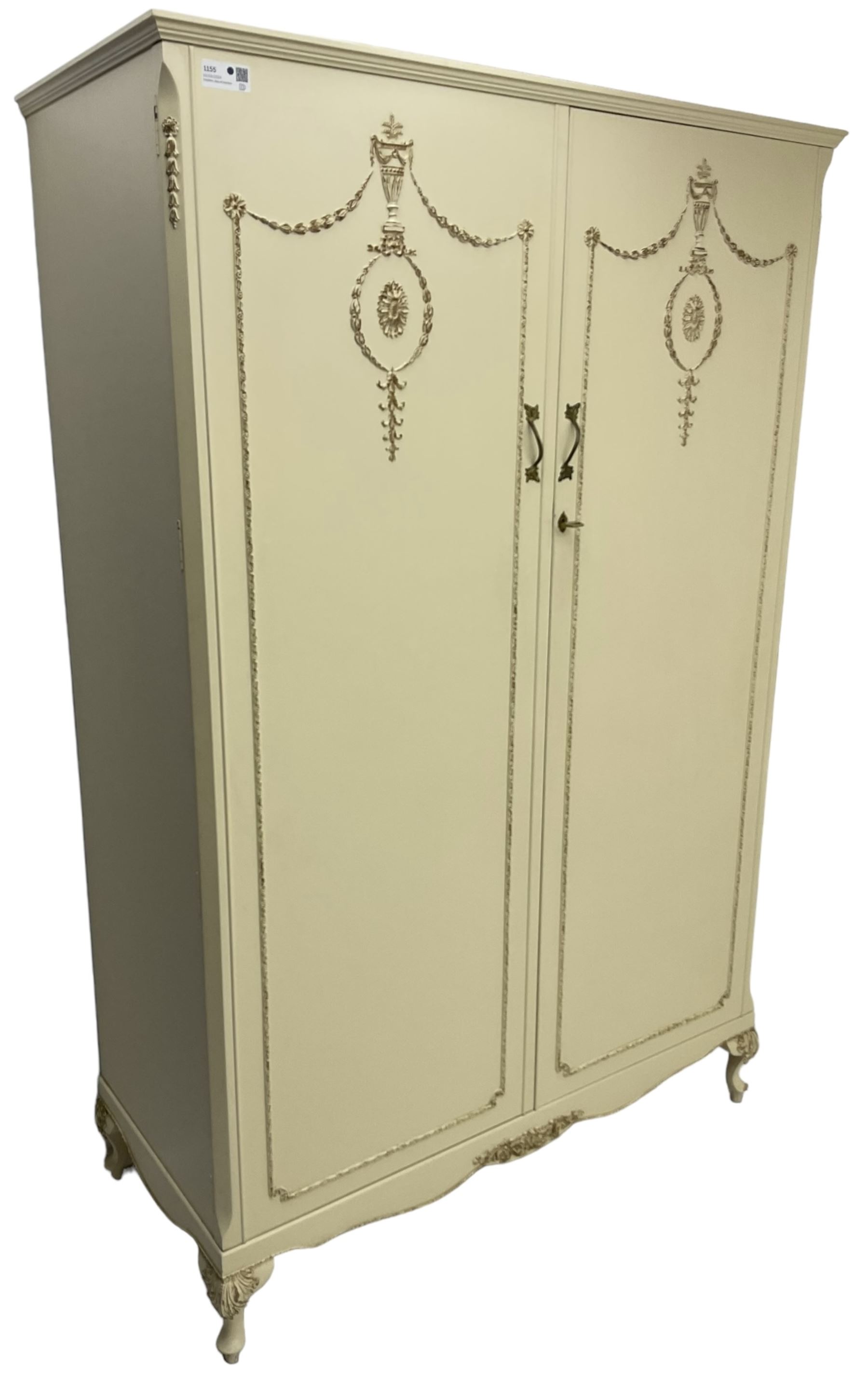 French classic design cream painted double wardrobe, the doors decorated with gilt and cream applied urn motifs with extending bell-flower festoons and ribbon twists, enclosing shelf and hanging rail, shaped apron on acanthus cabriole feet